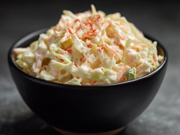 Cremiger Krautsalat mit Paprikapulver in schwarzem Schüssel, ideal als Beilage im Online Shop.